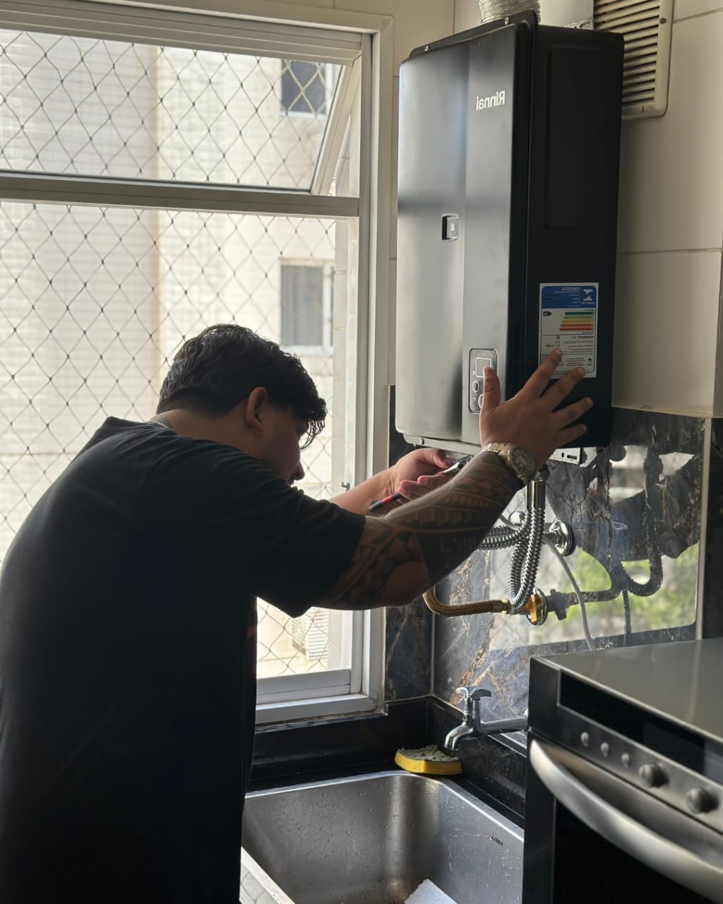 Técnico Inflame com uniforme posicionando duto de exaustão metálico em instalação de aquecedor Rinnai Continuum